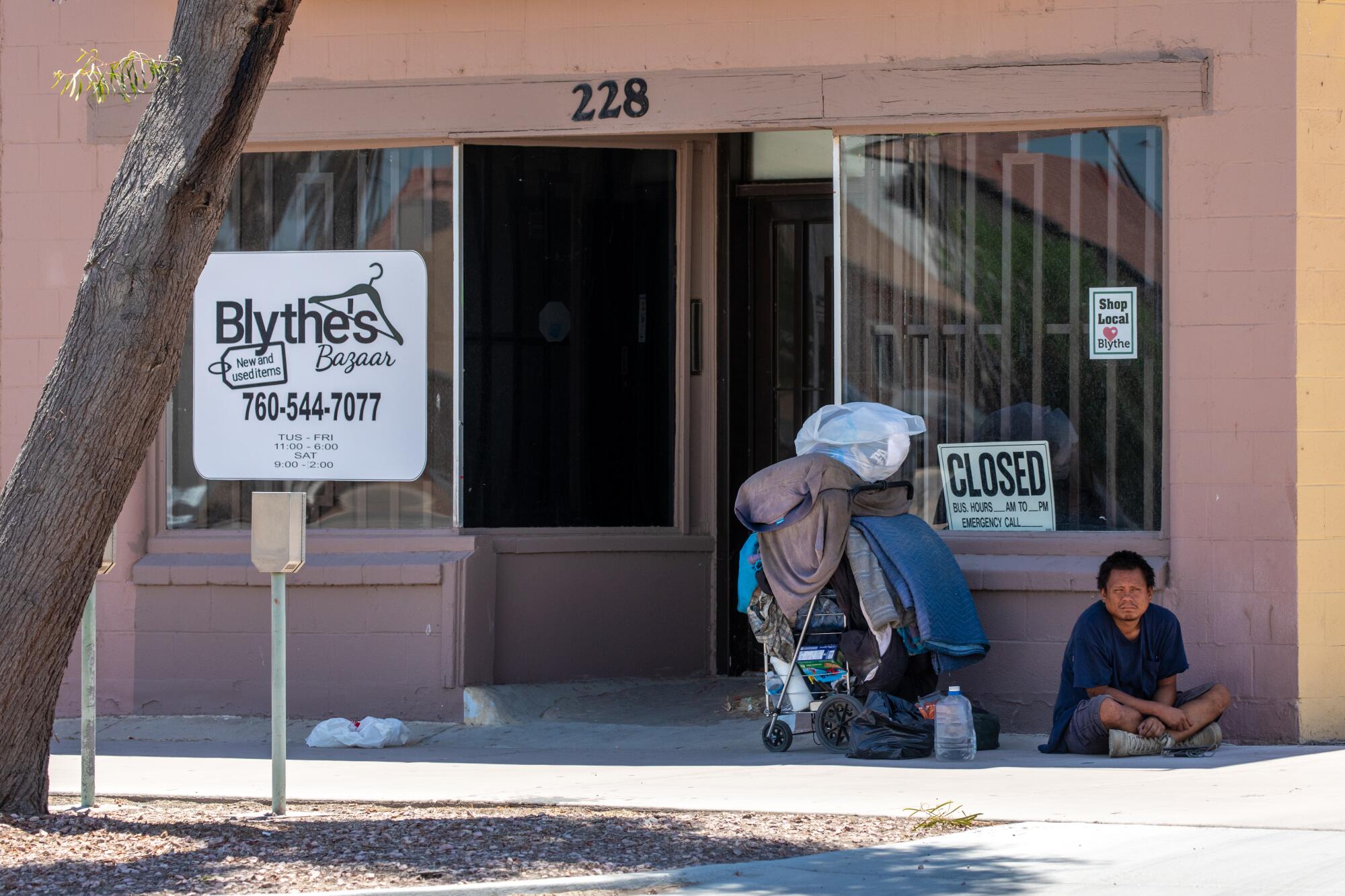 A homeless person finds shade in front of a building in Blythe.
