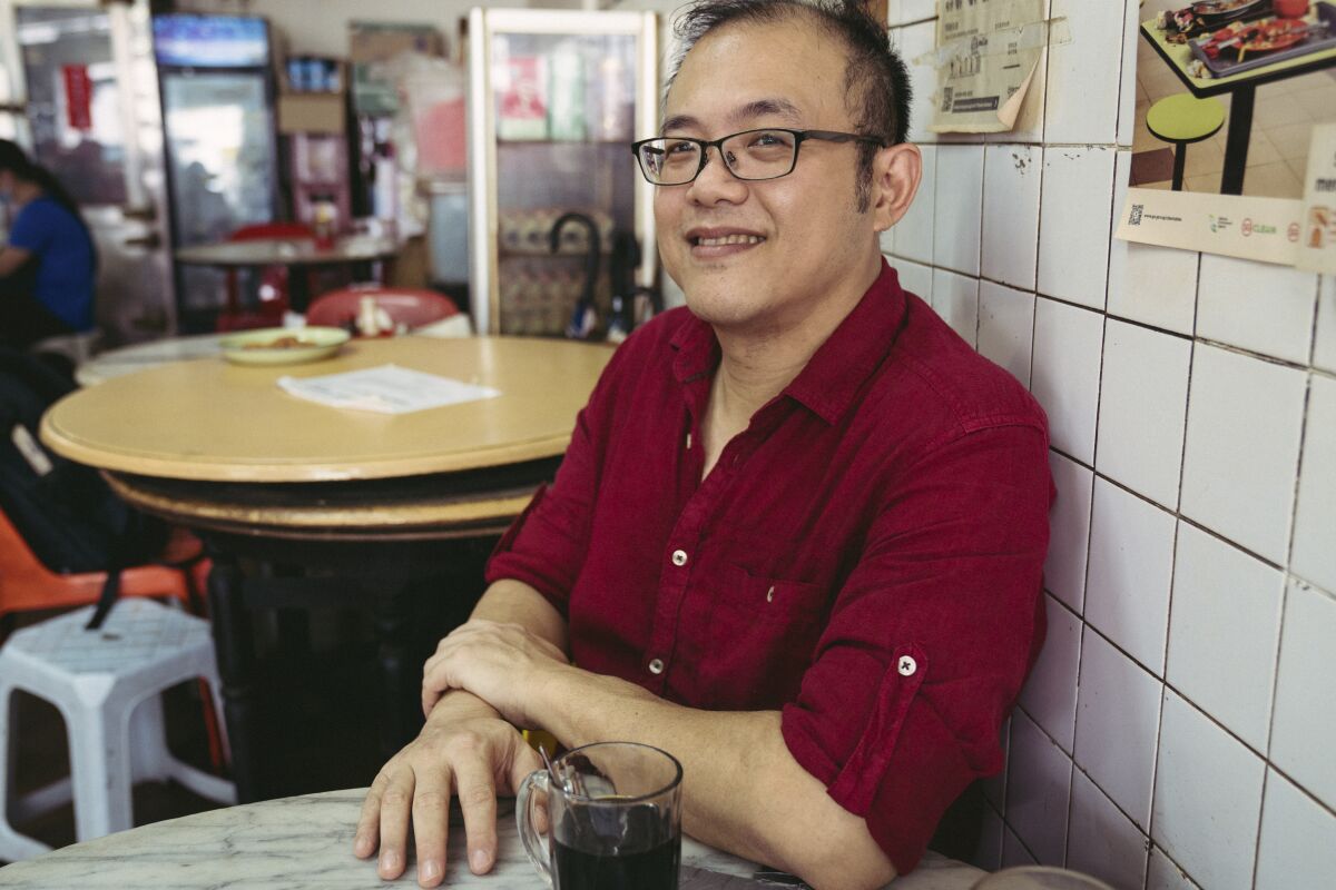 Christopher Tan, a Singaporean cookbook author, sits at a restaurant table.