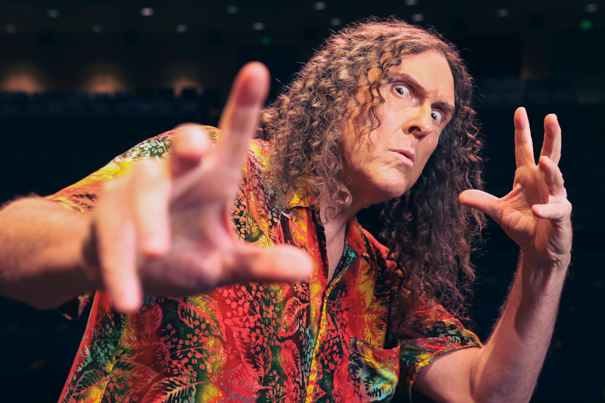 A man with long curly hair stares into the camera.