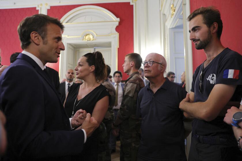 Henri, right, meets French President Emmanuel Macron in Annecy, French Alps, Friday, June 9, 2023. The 24-year-old man in France is being hailed as a hero after he intervened in a savage knife attack on very young children. Henri had a heavy backpack on his back and was holding another in his hand when the attacker slashed at him Thursday June 8, 2023. Henri was shown grappling with the assailant and charging after him during the knife attack that critically wounded four children between the ages of 22 months and 3 years old, and also injured two adults. (Denis Balibouse/Pool via AP)