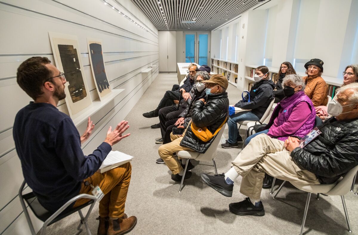 A mean speaks to a crowd seated in a narrow room.