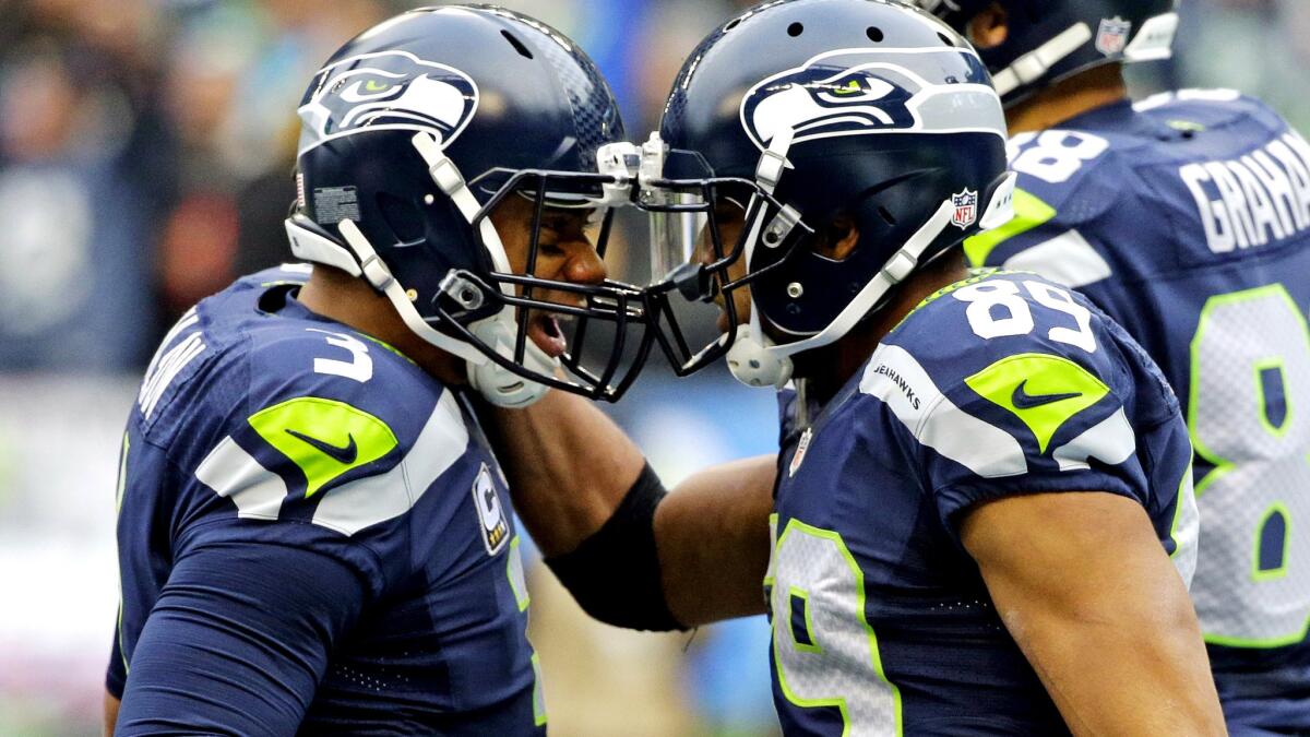 Seahawks quarterback Russell Wilson, left, celebrates with wide receiver Doug Baldwin after one of their two connections for a touchdown Sunday.