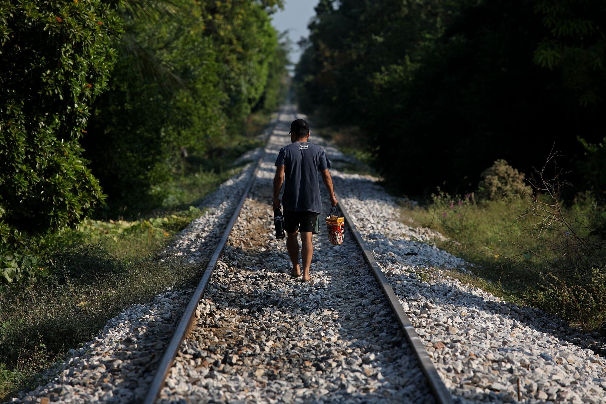 A man walks along the train tracks.