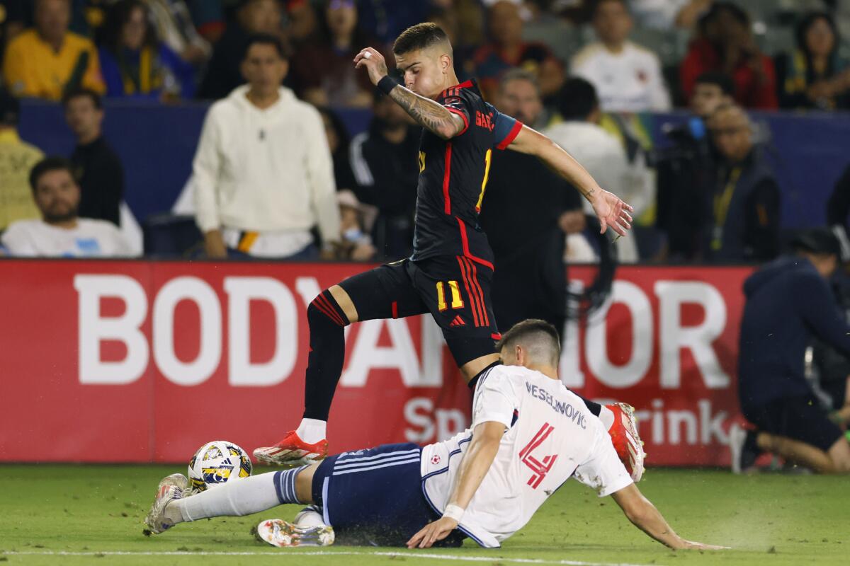 Vancouver's Ranko Veselinovic slide tackles Galaxy forward Gabriel Pec.