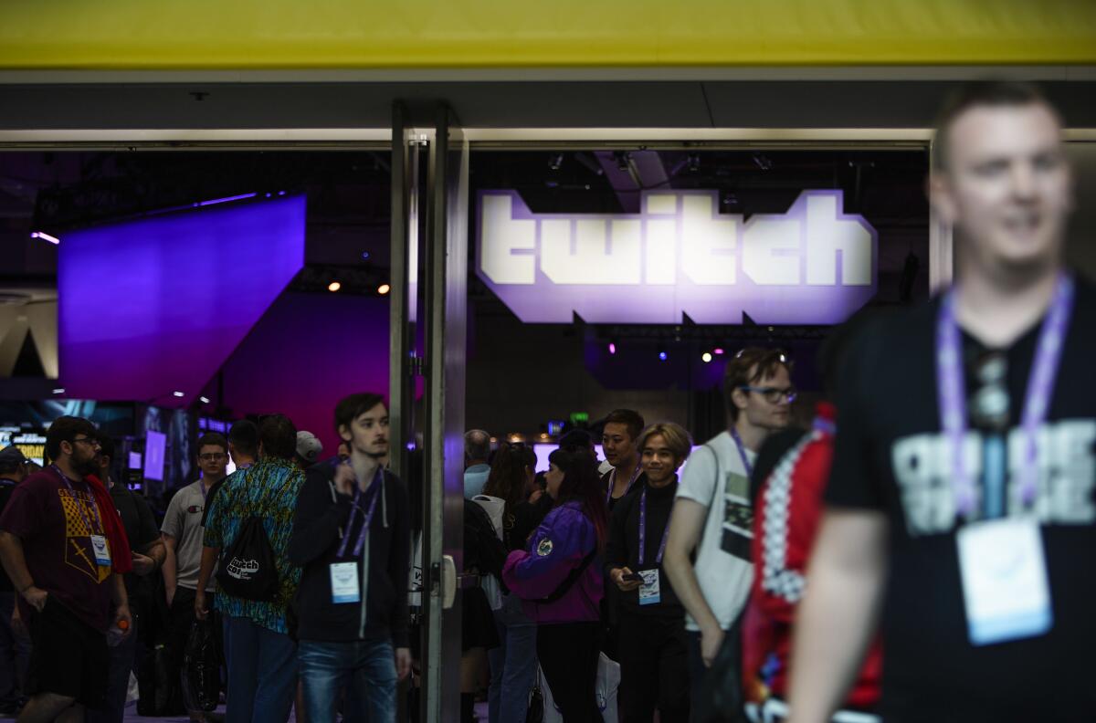 Through an exhibit hall's open doors a sign reading "Twitch" can be seen.