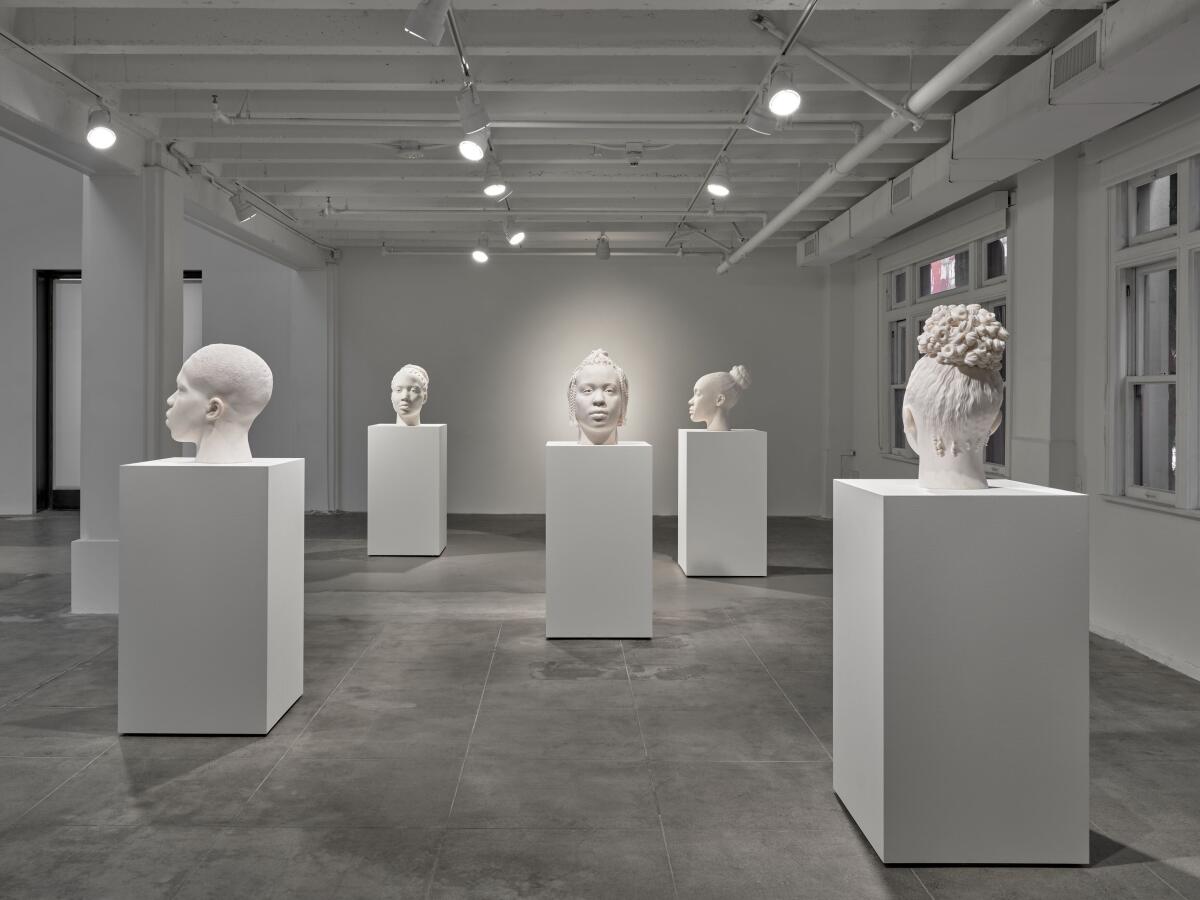 Pink marble busts of Black people are presented on plinths in a gallery