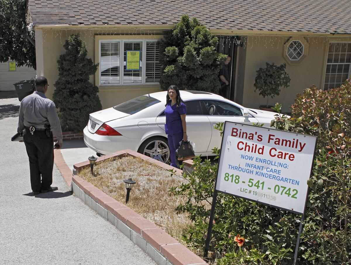 A woman who showed up to get some things out of the house at 3210 Orange Ave. speaks with Glendale Neighborhood Services and Glendale Police Dept. officials after Bina's Family Child Care was shut down at the home in La Crescenta on Wednesday, August 14, 2013. Officials posted a sign that said "LIMITED ENTRY. Occupancy Prohibited. No living, sleeping, cooking allowed. Entry limited for purposes of repair only."