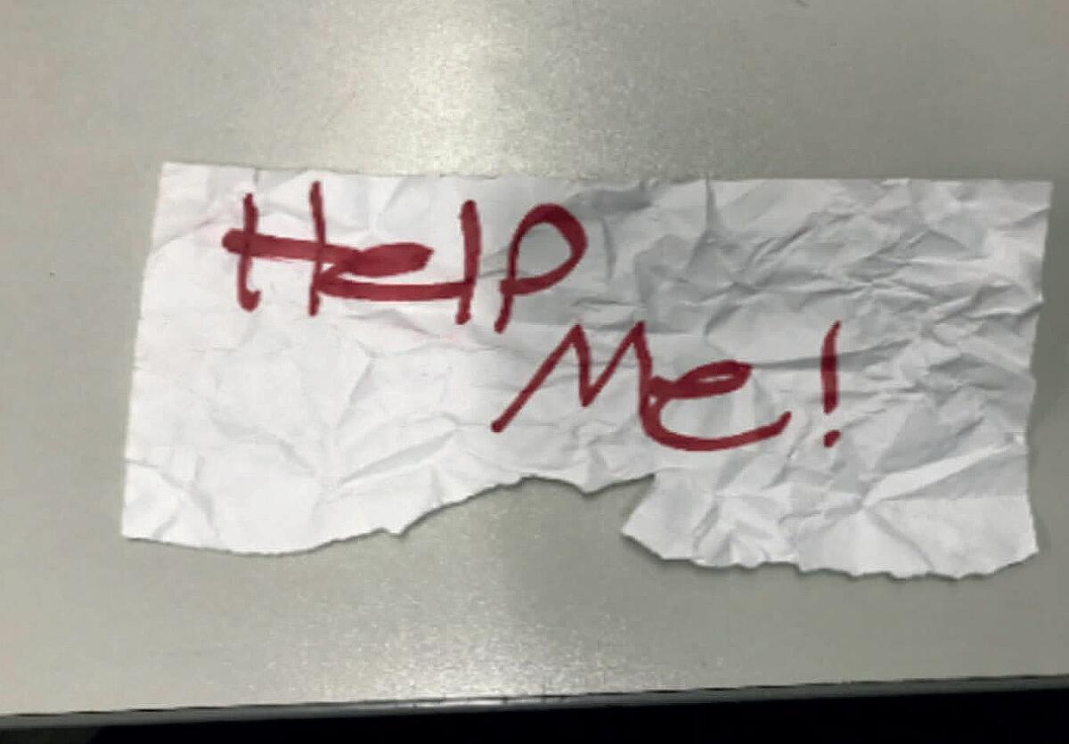 A wrinkled sheet of paper has red letters that say "Help me!"