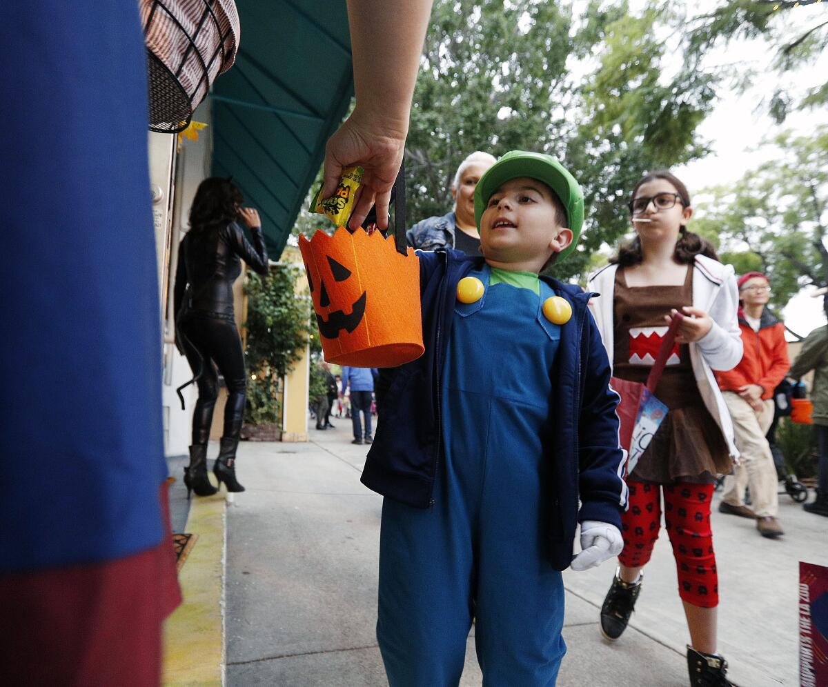 A little boy receives a piece of candy at an outdoor Halloween event.