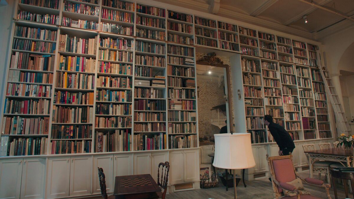 Adam Weinberger examining a bookshelf in "The Booksellers."
