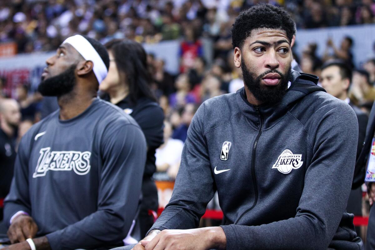 Lakers stars LeBron James, left, and Anthony Davis sit on the bench during an exhibition game against the Brooklyn Nets on Oct. 12.