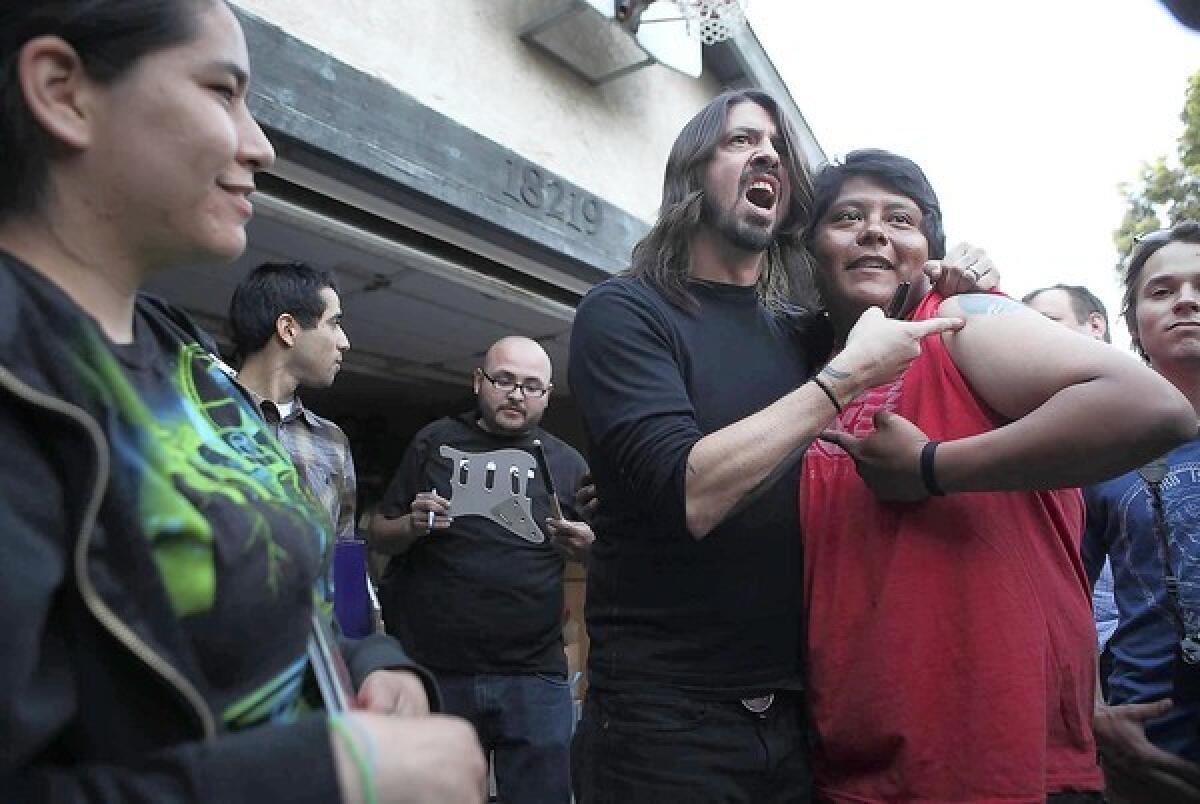 RABID FAN: Dave Grohl, center left, poses for pictures with a fan who has a Foo Fighters tattoo. The band will play two shows at the Forum this month.
