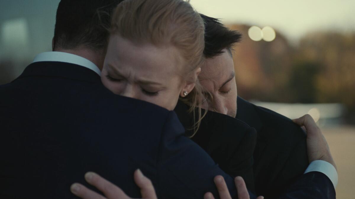 Wealthy siblings (played by Jeremy Strong, Sarah Snook and Kieran Culkin) embrace on a boat after learning their dad died.