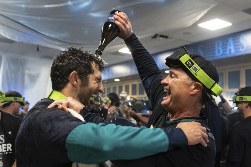 Seattle Mariners manager Scott Servais, right, celebrates in the clubhouse after the team's baseball game against the Oakland Athletics, Friday, Sept. 30, 2022, in Seattle. The Mariners won 2-1 to clinch a spot in the playoffs. (AP Photo/Stephen Brashear)