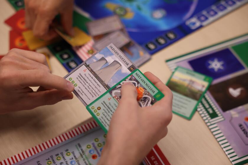 El Segundo, CA - July 18: Science Desk Intern Noah Haggerty holds cards as he plays with other environmental reporters an environmental board game at Los Angeles Times Headquarters on Thursday, July 18, 2024 in El Segundo, CA. (Michael Blackshire / Los Angeles Times)