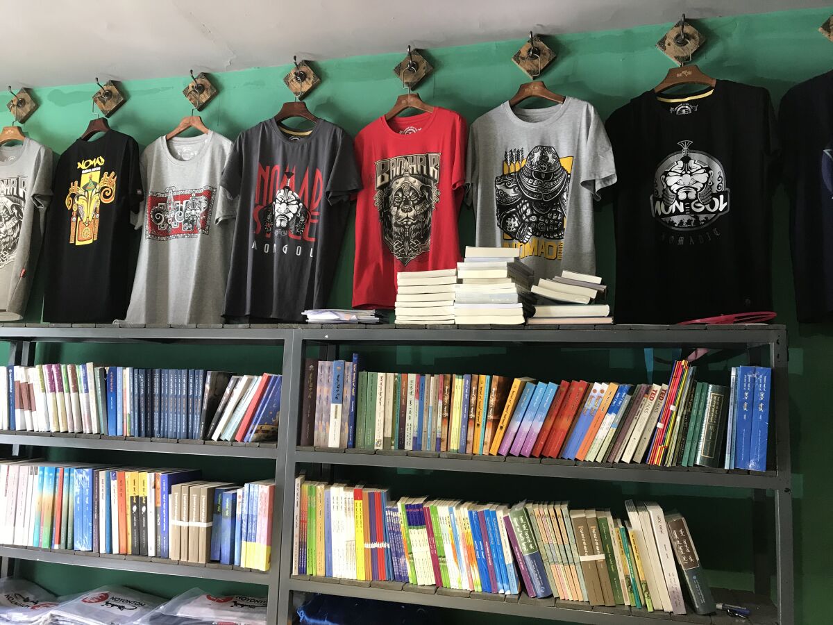 A shop sells T-shirts with popular Mongolian symbols and band names, and Mongolian-language books.