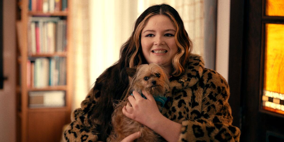 A woman in a leopard-print coat holding a dog.