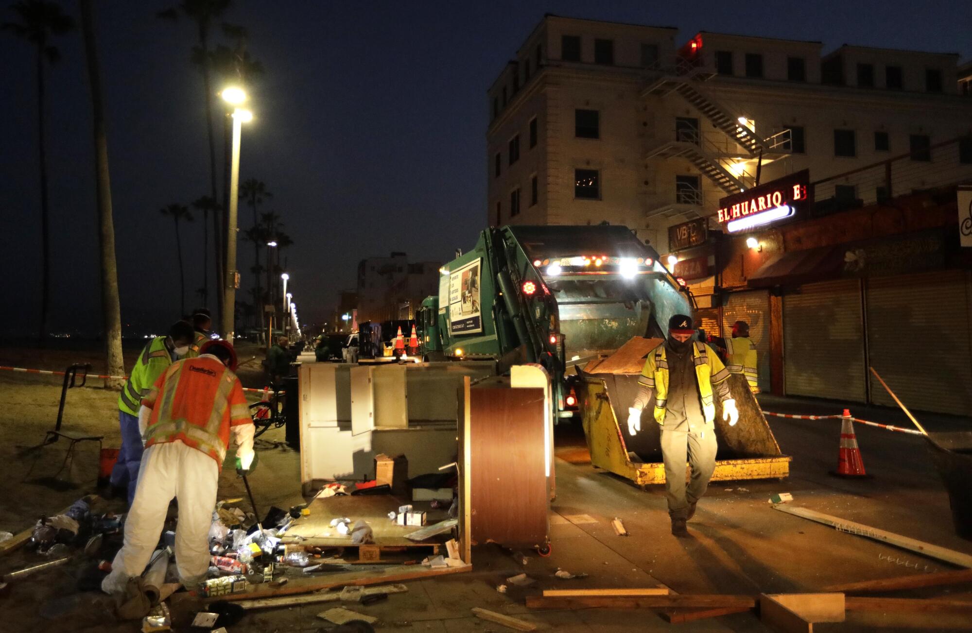 Sanitation workers clear a homeless encampment along Ocean Front Walk in Venice.