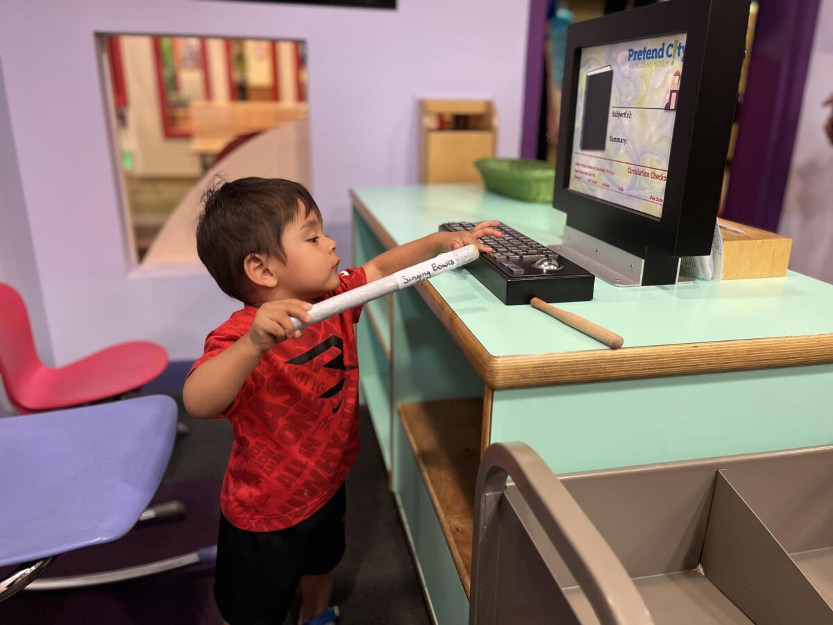 A child plays with a toy computer at Pretend City Children’s Museum in Irvine.