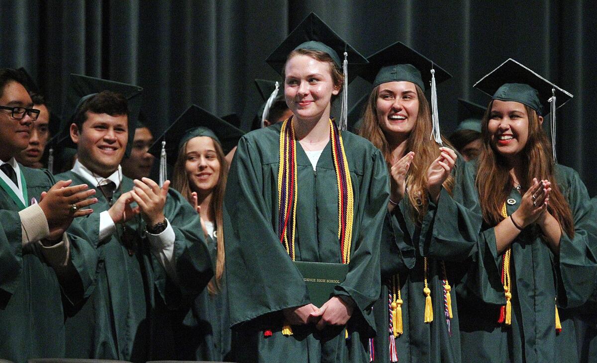 Standing with her diploma in hand, graduate Olivia Menke receives a minutes-long standing ovation from her fellow graduating classmates at a Providence High School graduation ceremony recreated just for her at the Hall of Liberty at Forest Lawn in Los Angeles on Aug. 6, 2015.