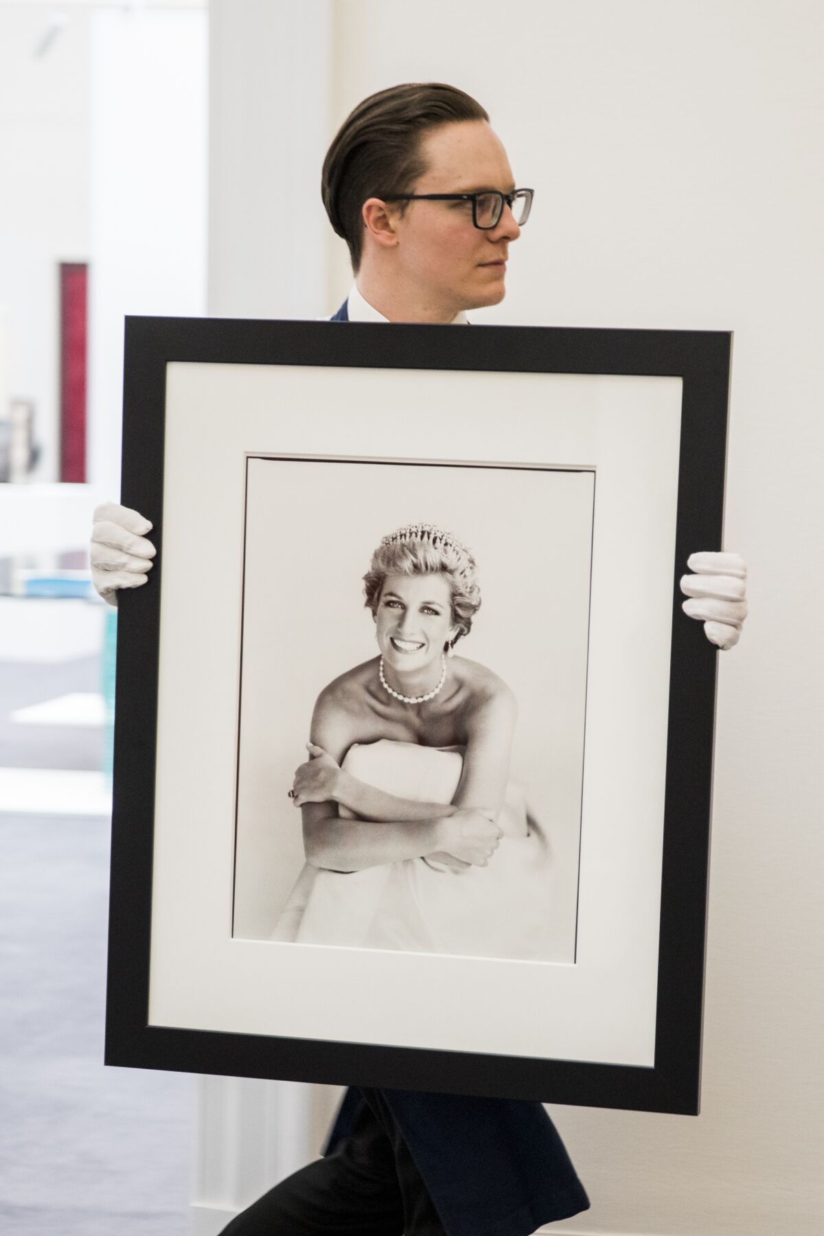 Patrick Demarchelier's Princess Diana photo is carried by a man wearing white gloves.