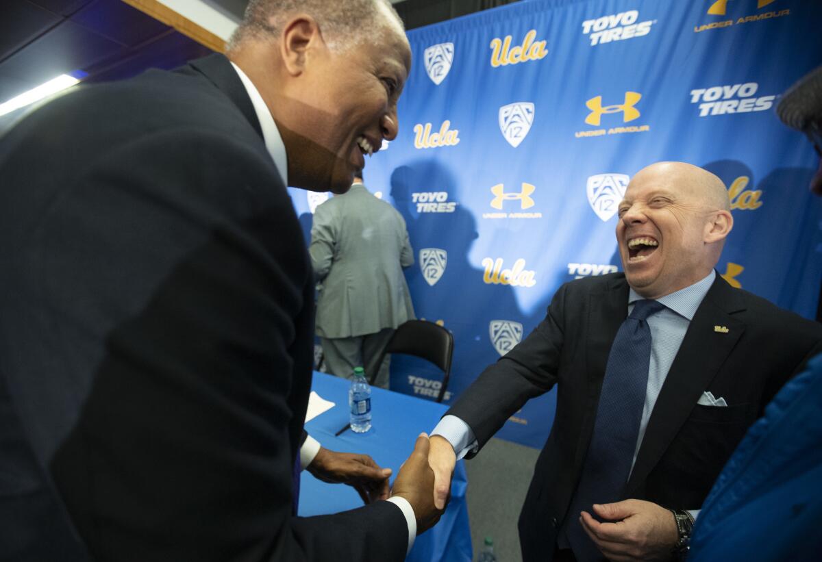 New UCLA coach Mick Cronin, right, shares a light moment with former Bruins player Jamaal Wilkes.
