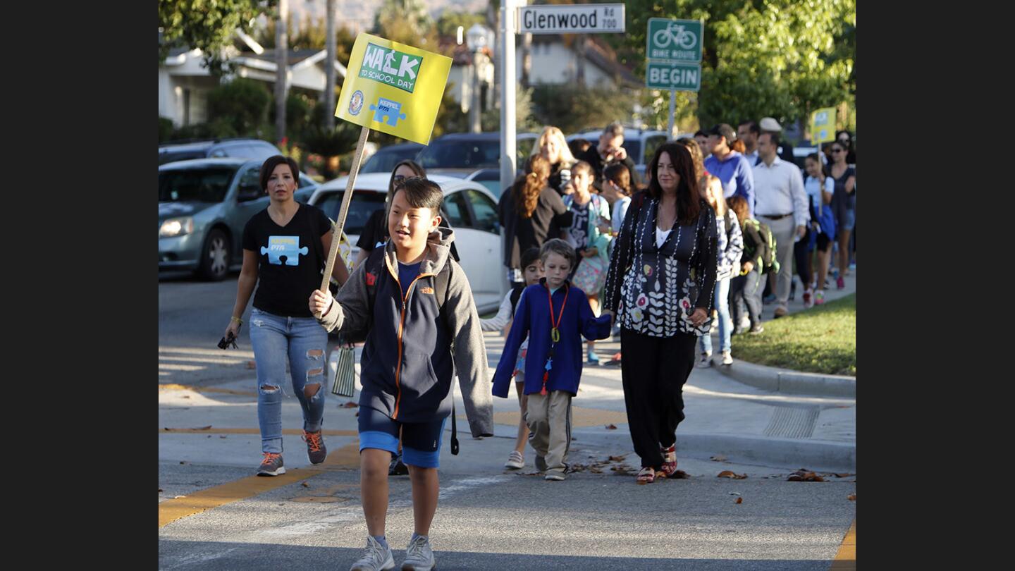 Fourth grader Tyler Hong, 9, carries a Walk To School sign as he leads many other students and parents toward Keppel Visual and Performing Arts Magnet, Toll Middle School and Hoover High School on International Walk to School Day in Glendale on Wednesday, Oct. 4, 2017.
