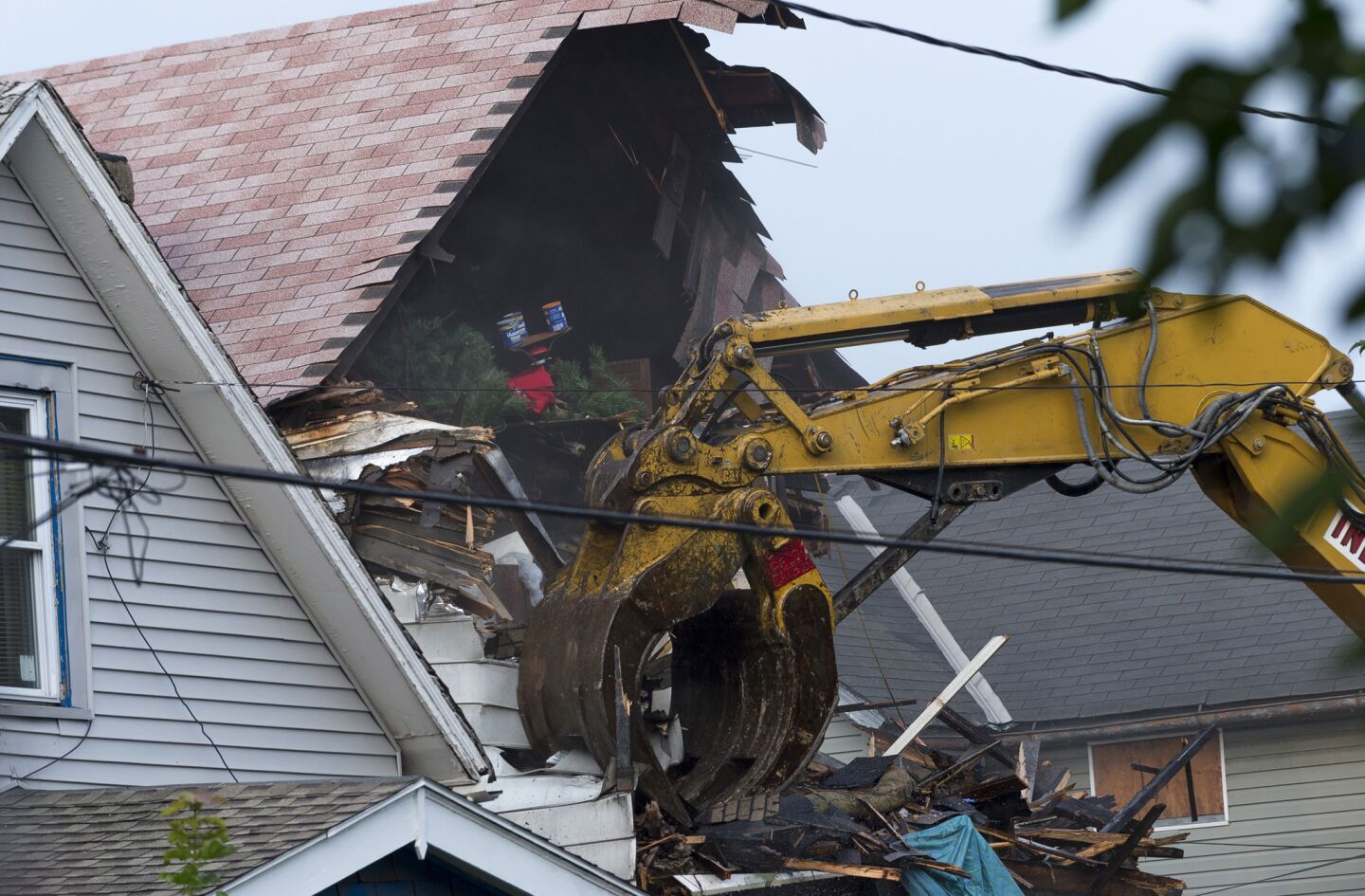 The attic of Ariel Castro's home is torn open by an excavator, exposing personal items inside.