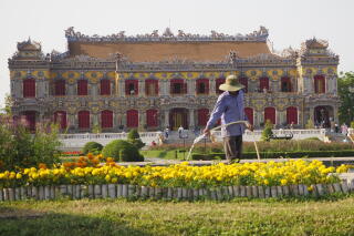 A gardener waters flowers outside the newly rebuilt Kien Trung Palace