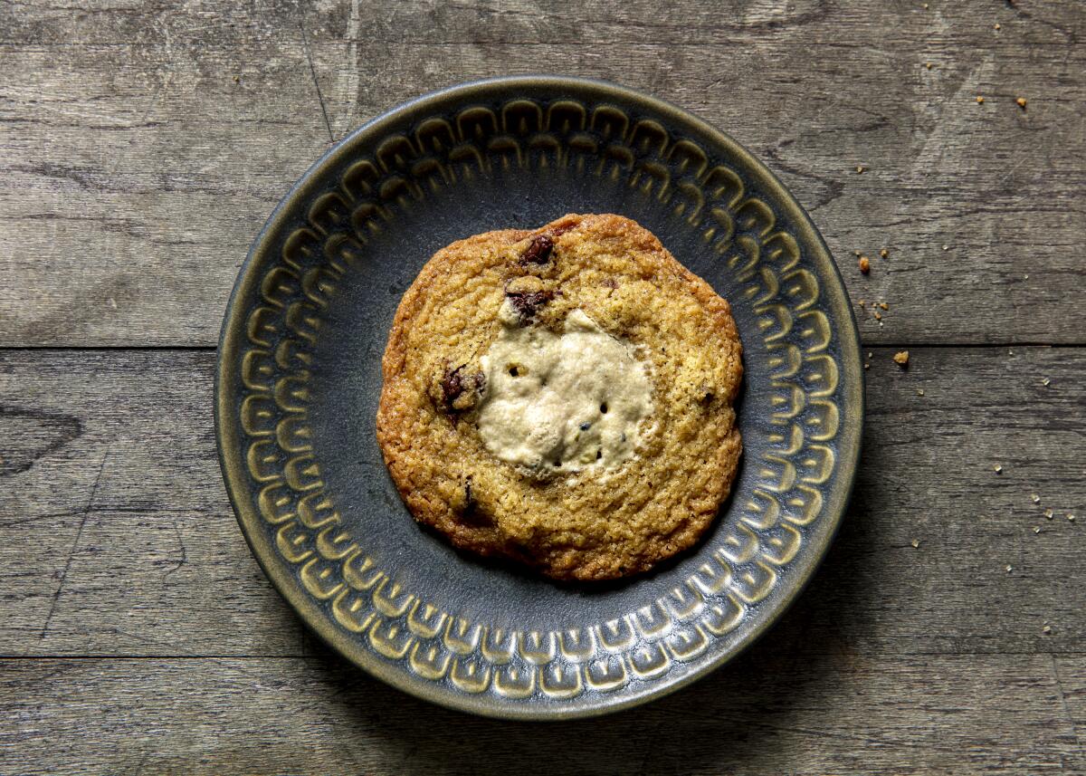 A Halva Cardamom Chocolate Chip Tahini Cookie on a dark gray plate.