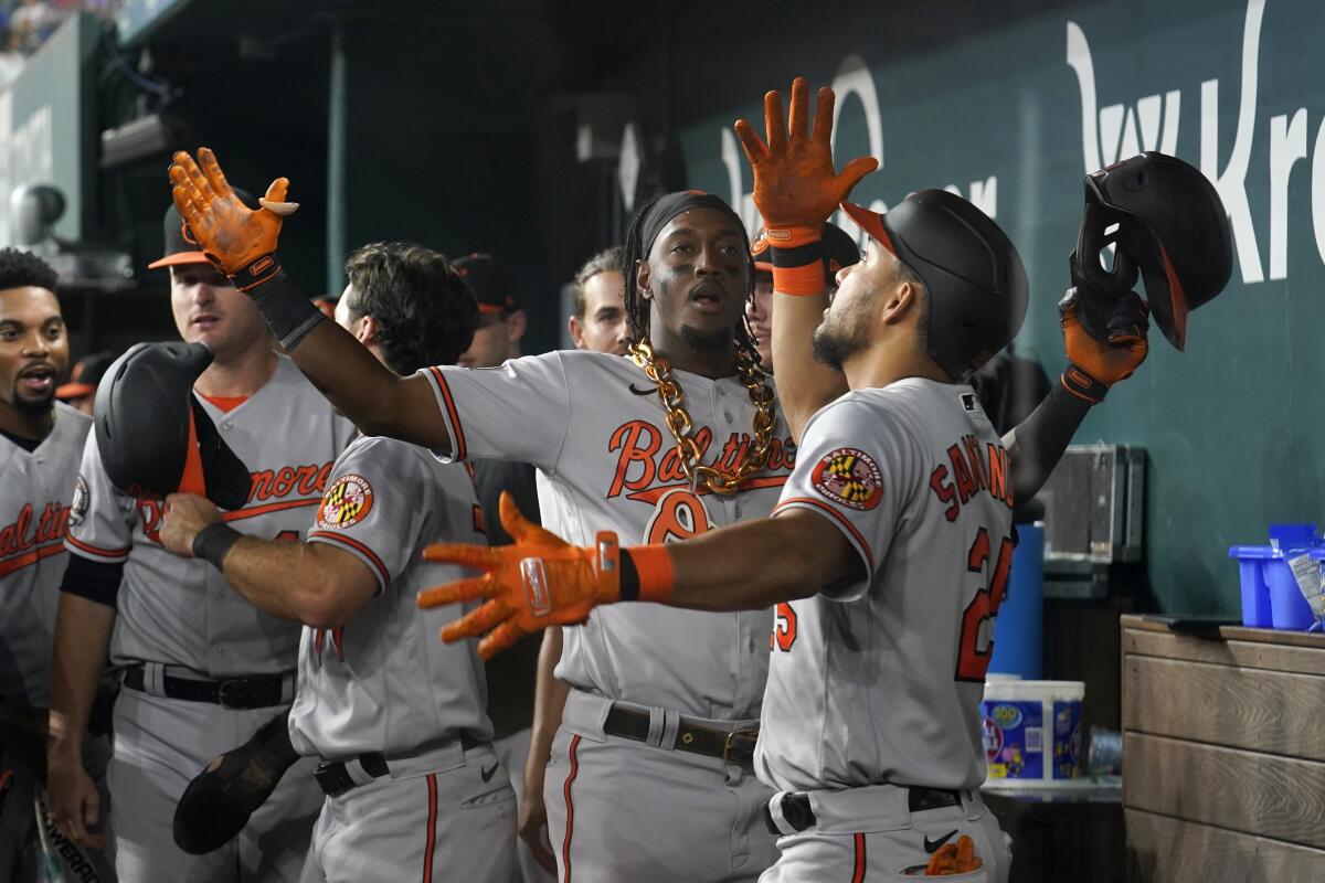 Baltimore Orioles shortstop Jorge Mateo, center, and Anthony Santander, right, celebrate in the dugout after Mateo hit a two-run home run in the ninth inning of a baseball game against the Texas Rangers, Tuesday, Aug. 2, 2022, in Arlington, Texas. The shot also scored Terrin Vavra. (AP Photo/Tony Gutierrez)