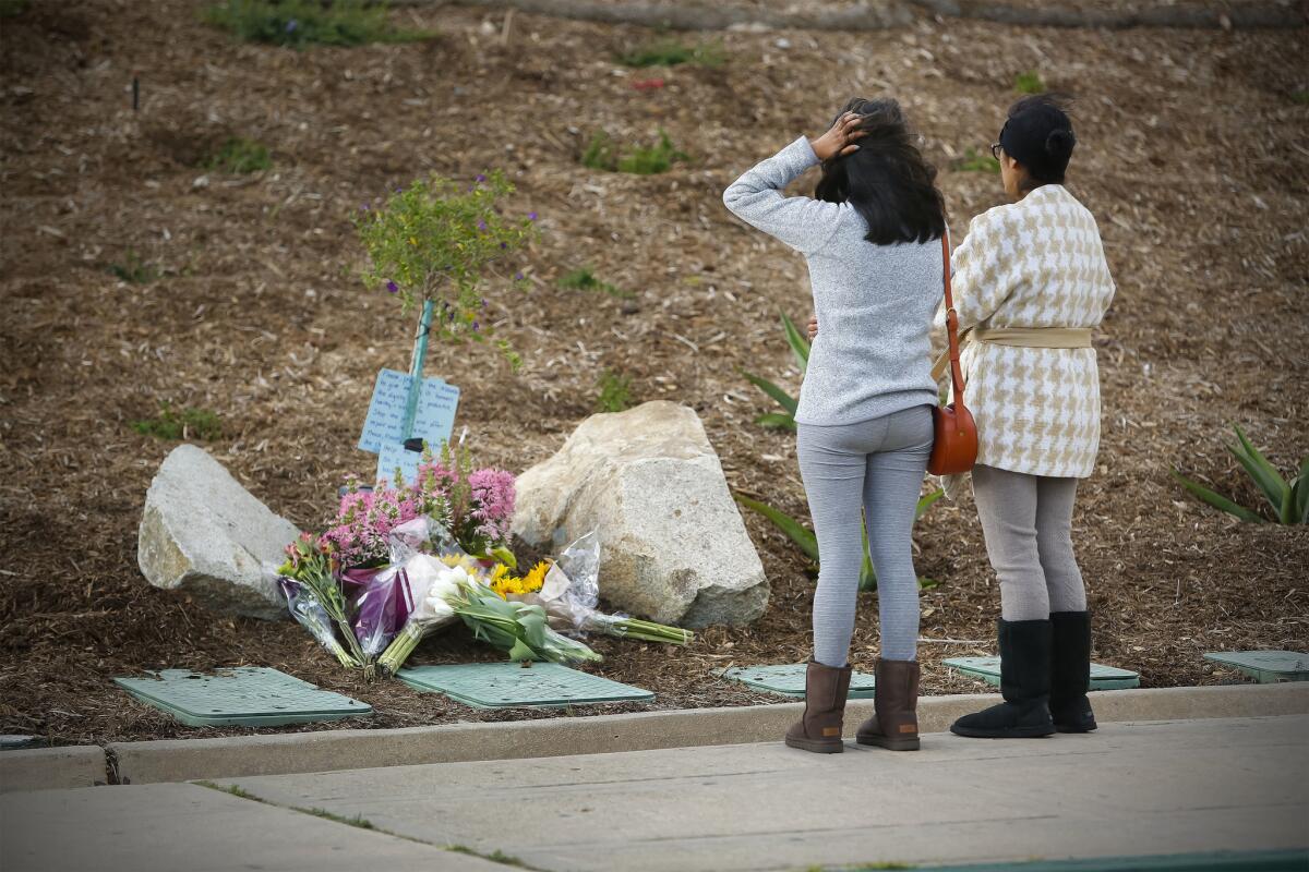 A mother and daughter pay their respects at a memorial of flowers that is starting to grow in front of Torrey Pines High School near where a 9th-grader at the school was shot and killed by San Diego Police officers. (Howard Lipin / San Diego Union-Tribune)