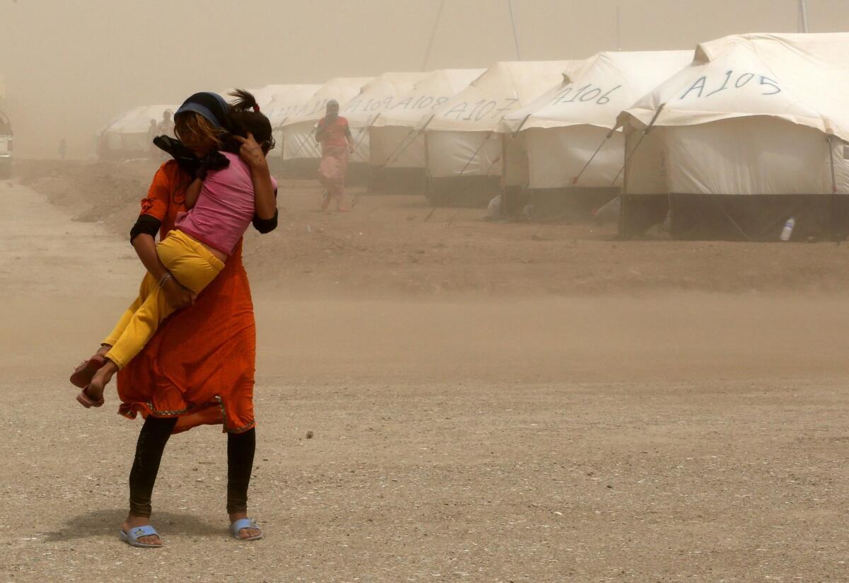 An internally displaced Iraqi woman holds her sister during a sandstorm at a new camp outside the Bajid Kandala camp in Feeshkhabour town, Iraq, Tuesday, Aug. 19, 2014. Some 1.5 million people have been displaced by fighting in Iraq since the Islamic State's rapid advance began in June, and thousands more have died. The scale of the humanitarian crisis prompted the U.N. to declare its highest level of emergency last week. (AP Photo/ Khalid Mohammed) The Associated Press