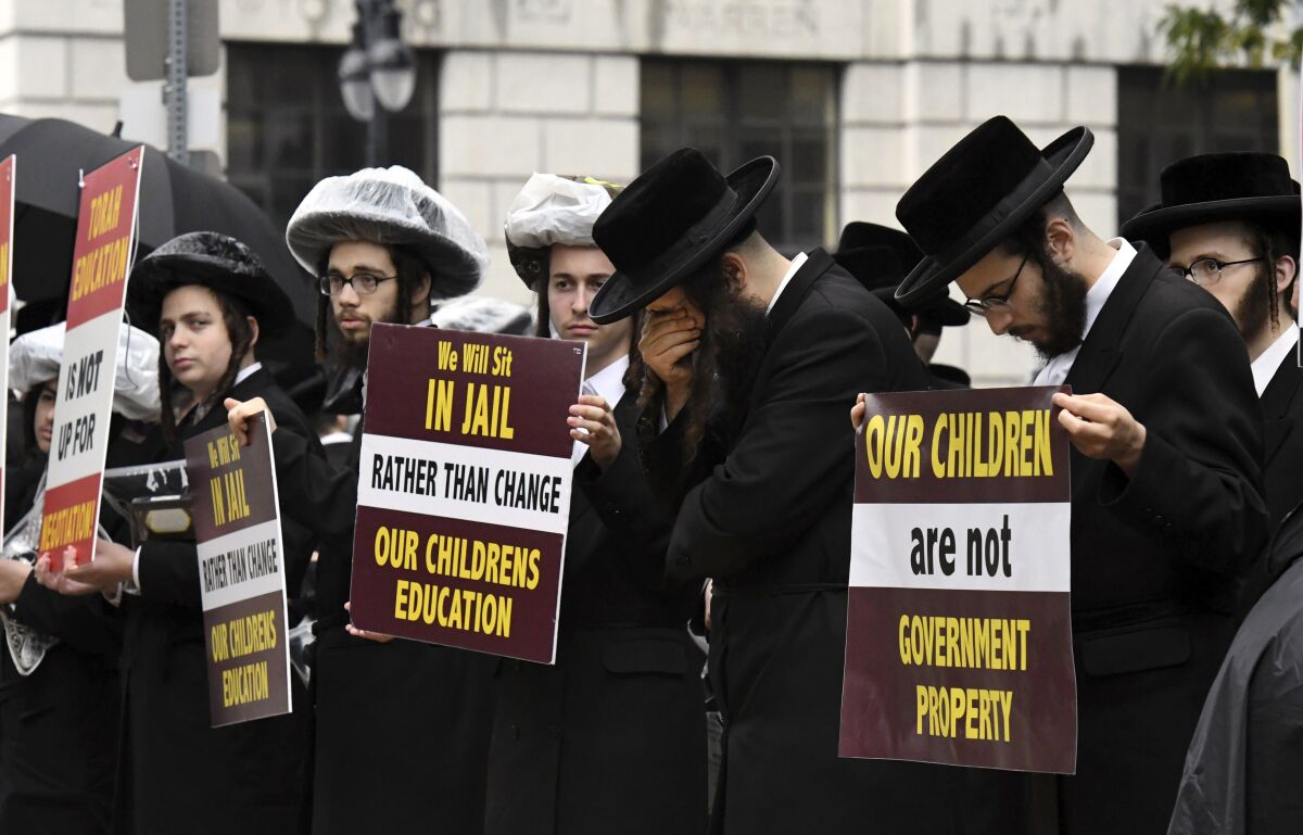 FILE - Members of the ultra-Orthodox and Hasidic Jewish communities protest before a Board of Regents meeting to vote on new requirements that private schools teach English, math science and history to high school students, Sept. 12, 2022, outside the New York State Education Department Building in Albany, N.Y. Parents cannot be required to pull their children from private schools that fail to meet state-designated standards, a judge decided Thursday, March 23, 2022, striking down a key provision of rules recently passed to strengthen oversight of private and religious schools in New York. (Will Waldron/The Albany Times Union via AP, File)