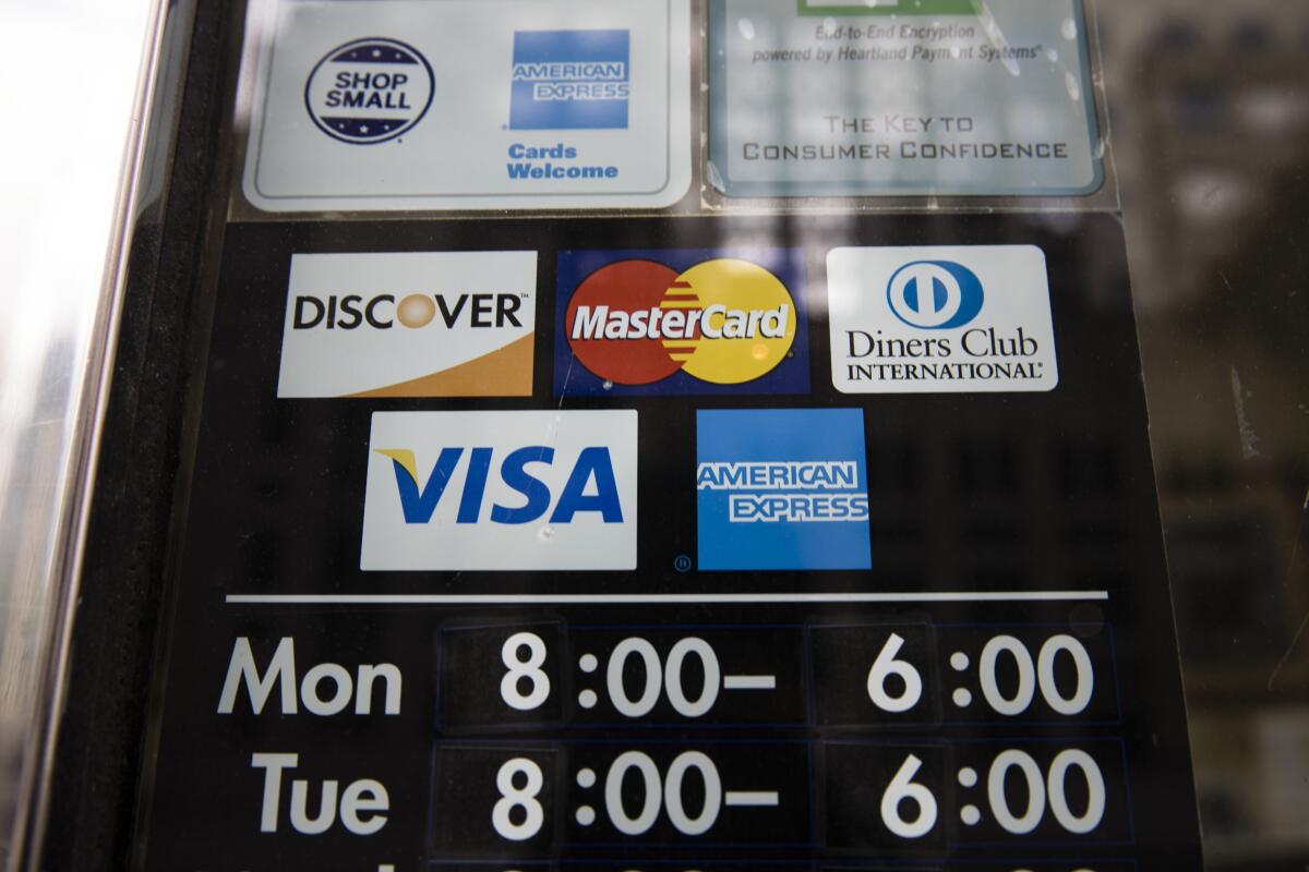 Credit card options are shown on a store's door. 