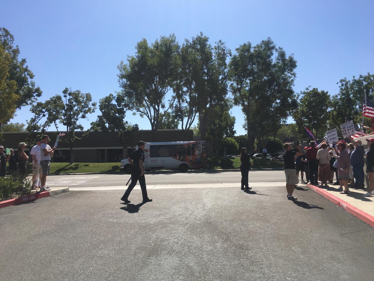 President Trump supporters, right, and opponents disagree about the impeachment inquiry from across an Irvine street Friday afternoon.