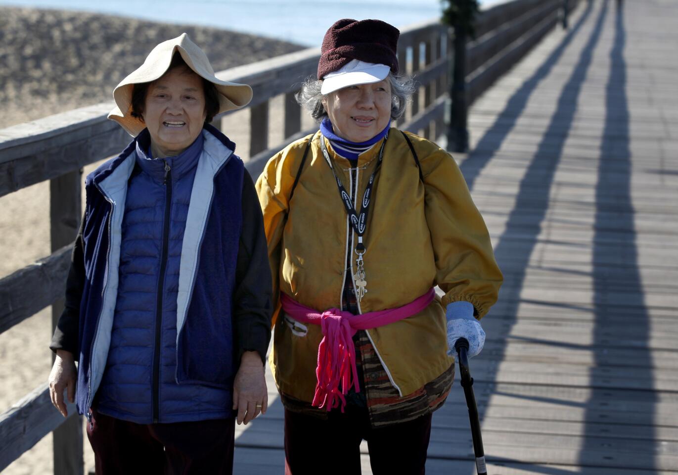 In winter coats and hats, Ziao Pham, left, and her sister Thoa Pham, both of Fountain Valley, walk on the Seal Beach Pier on Dec. 30.