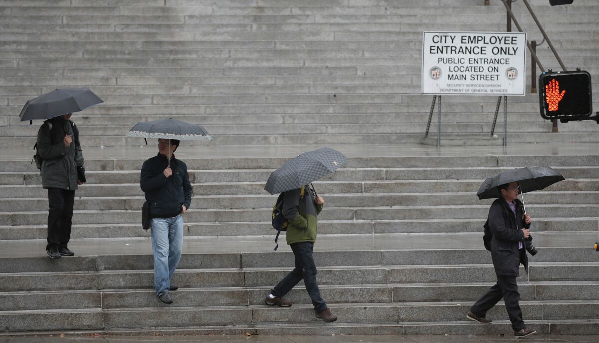Visitors walk along the steps of City Hall as rain falls in downtown Los Angeles.