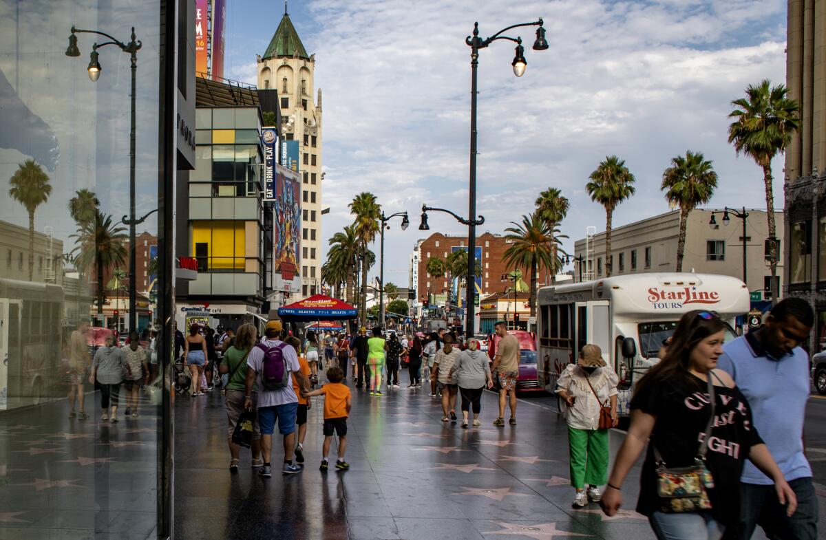 A lot pedestrians on a wide sidewalk.
