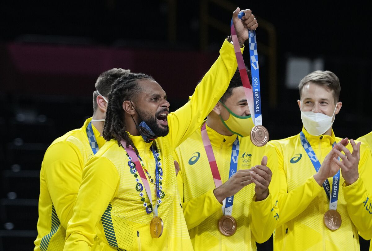 Australia's Patty Mills holds up a bronze medal for a teammate who was injured and left the game early after beating Slovenia in the men's bronze medal basketball game at the 2020 Summer Olympics, Saturday, Aug. 7, 2021, in Tokyo, Japan. (AP Photo/Eric Gay)