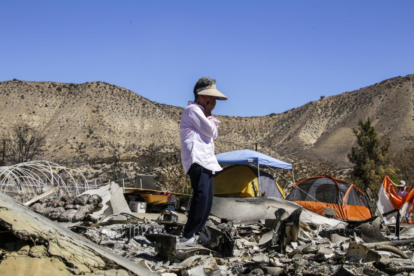 Sarah Choi, 70, stands over the charred remains of her home. She and her husband are living in tents after the Blue Cut fire swept through the West Cajon Valley.