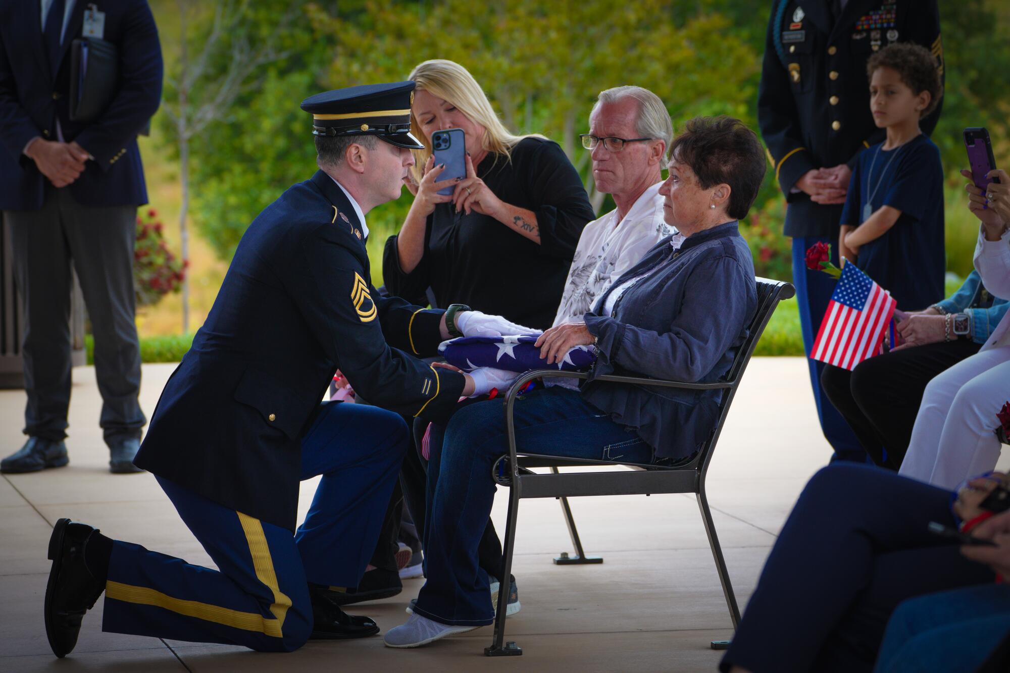 A member of the U.S. Army National Guard Honor Guard presents a folded U.S. flag to Marcia McKeon.