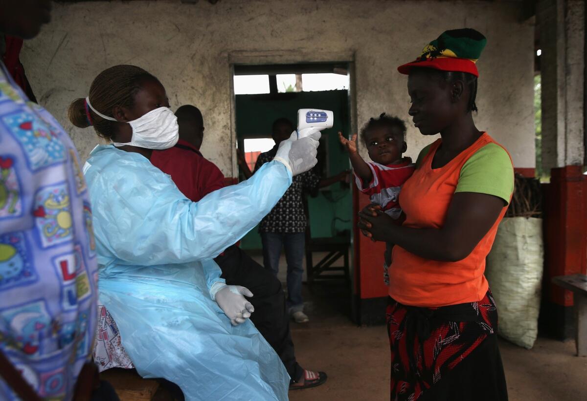 A Liberian Health Ministry worker checks people for Ebola symptoms in Dolo Town.