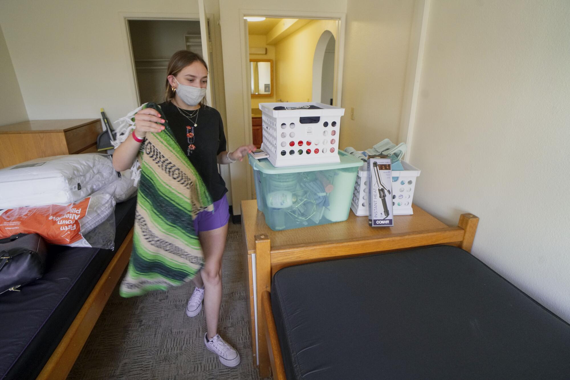 Sage Greve, from Switzerland, prepares to make her bed in her dorm room at USD