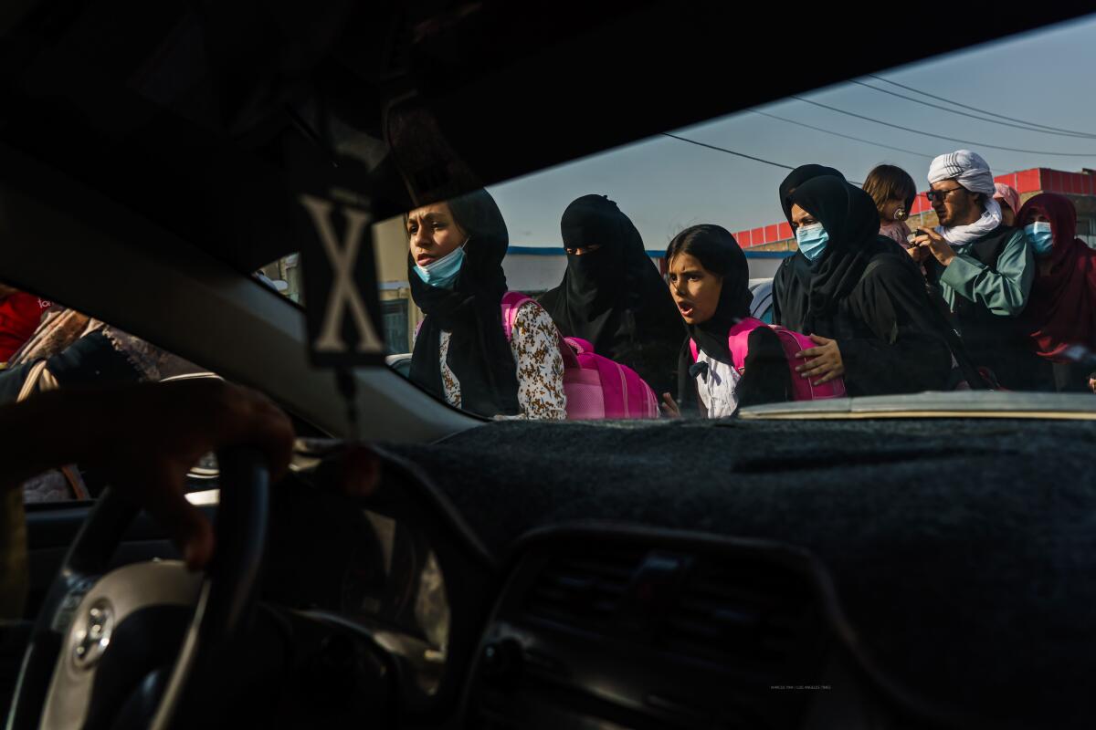 Women and girls are seen through a car windshield