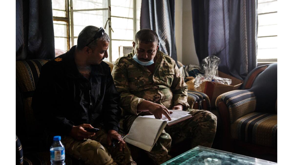 Maj. Tarek Gazali, left, is briefed by a fellow medic on civilian injuries treated at a field clinic operated by medics from the Iraqi Emergency Response Division and NYC Medics.
