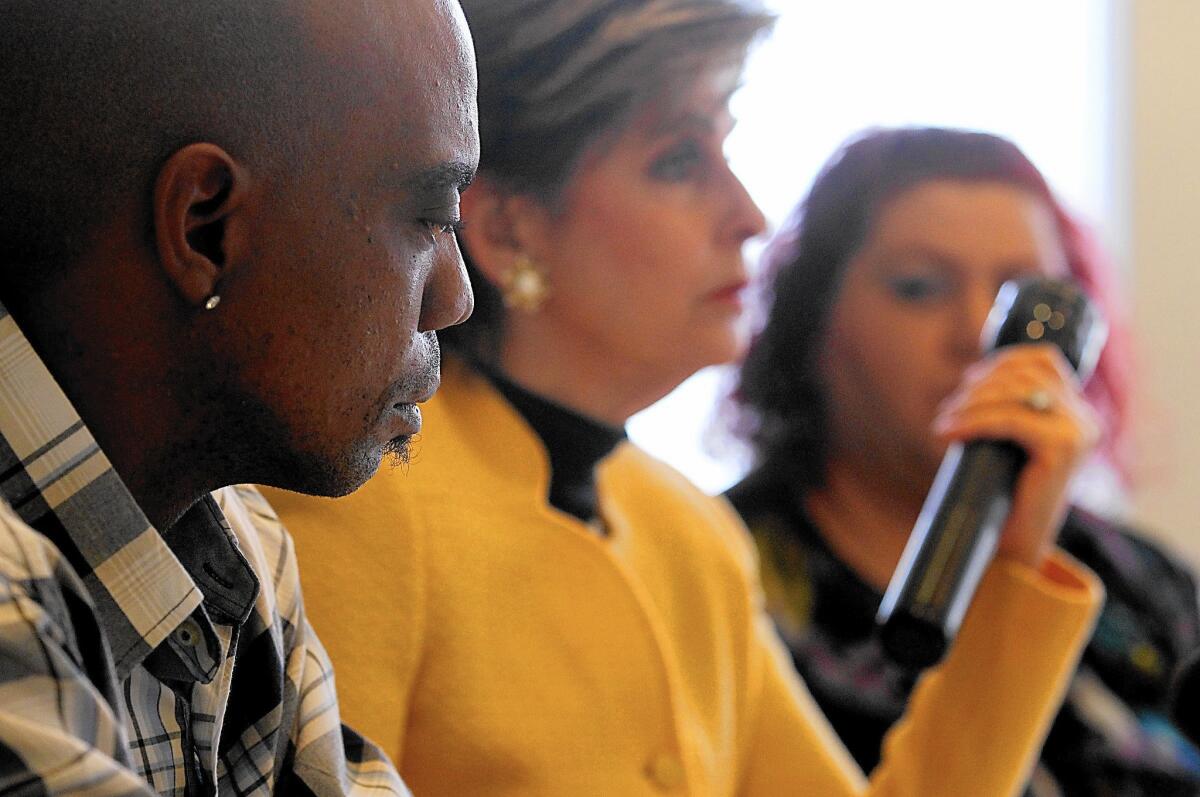 Bret Phillips, left, with attorney Gloria Allred in 2014. Allred holds a flashlight of the same type that Phillips was allegedly beaten with.
