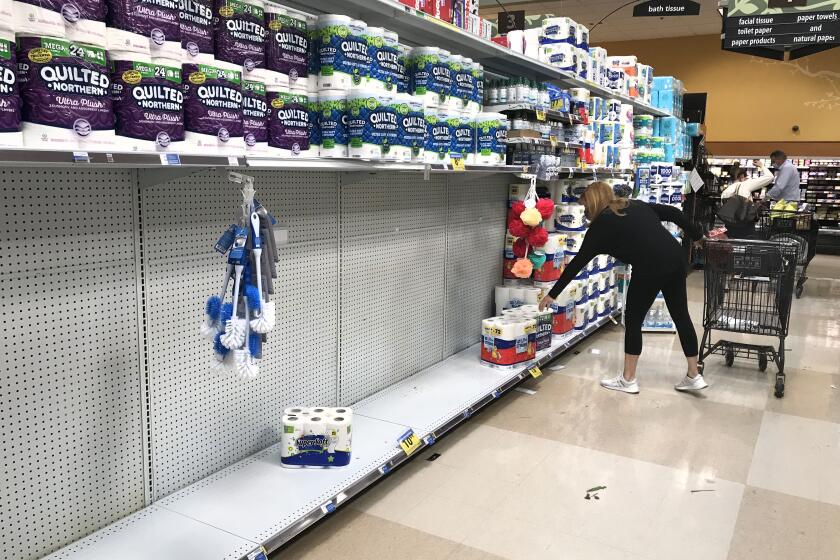 CALABASAS, CA - NOVEMBER 192020: A shopper reaches for a roll of toilet paper on a partially empty shelf at Ralph's market in Calabasas. (Mel Melcon / Los Angeles Times)