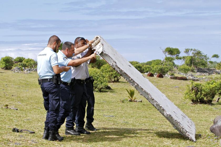French police on Reunion Island inspect a piece of aircraft debris found on July 29.