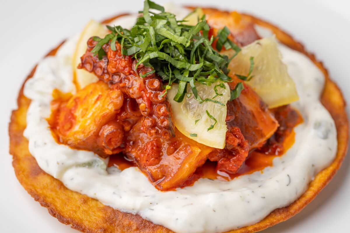 An octopus tostada topped with herbs and preserved lemon.